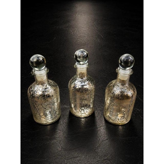 A beautiful matching set of three vintage mercury-style glass apothecary bottles or decorative decanters, each retaining...
