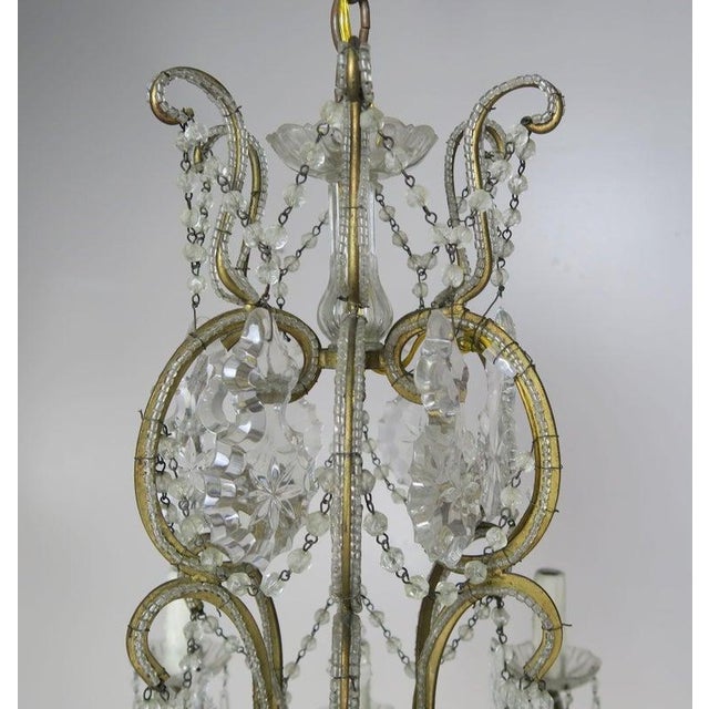 10-light French Louis XV style crystal beaded chandelier, circa 1930s. The chandelier is adorned with etched cut pendulum...