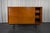 This teak veneered sideboard rests on a black lacquered metal structure, offers 3 levels of shelves and closes with a...
