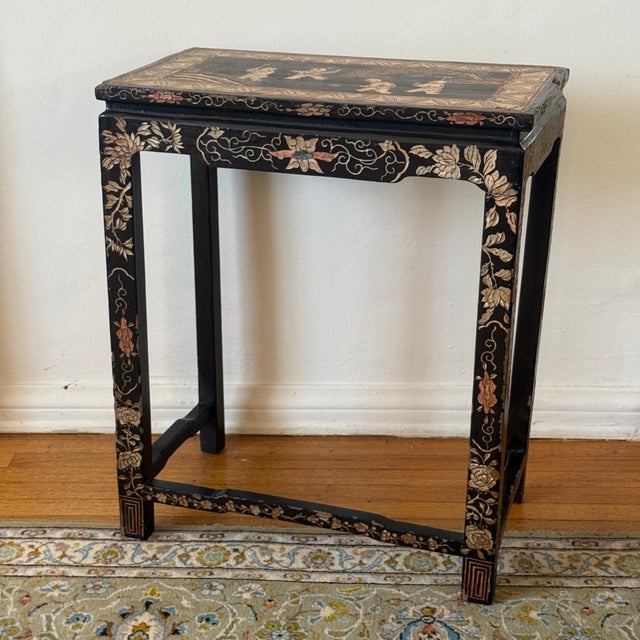 Antique Chinese black lacquer accent table featuring hand-painted floral decoration and a decorative figural scene to the...