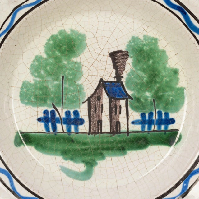 An early 19th century French glazed earthenware plate from Rouen, with a hand-painted country house in blue, grey and...