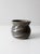 A vintage studio pottery vase finished in deep grey tones with a soft cinched shape that feels balanced and sculptural....