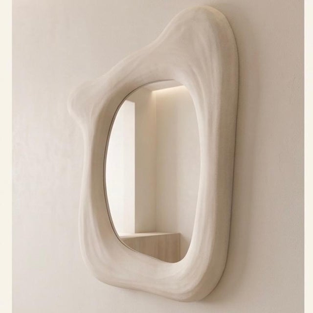 An organic plaster‑of‑Paris mirror shaped by hand, where soft curves and natural texture catch the light with quiet...