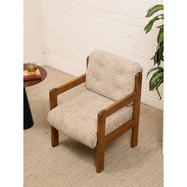A wonderfully substantial vintage armchair with a chunky exposed wood frame and beautifully textured cream upholstery.