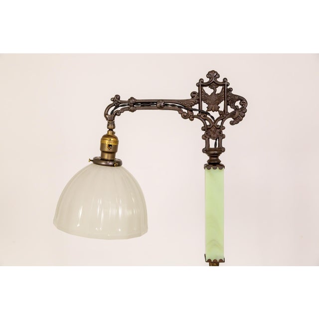 An early 20th-century bridge-style floor lamp of decorative cast iron and yellow-green uranium glass. The top has an...
