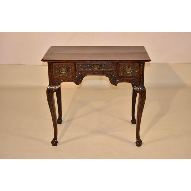 Early 18th century hand carved oak lowboy from England. The top is made from two planks, with shaped corners, which adds...