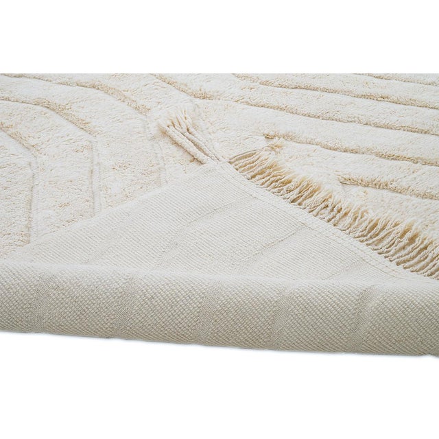 Refined hand-knotted wool rug featuring a radiant geometric pattern in soft ivory hues. This timeless design adds elegance...