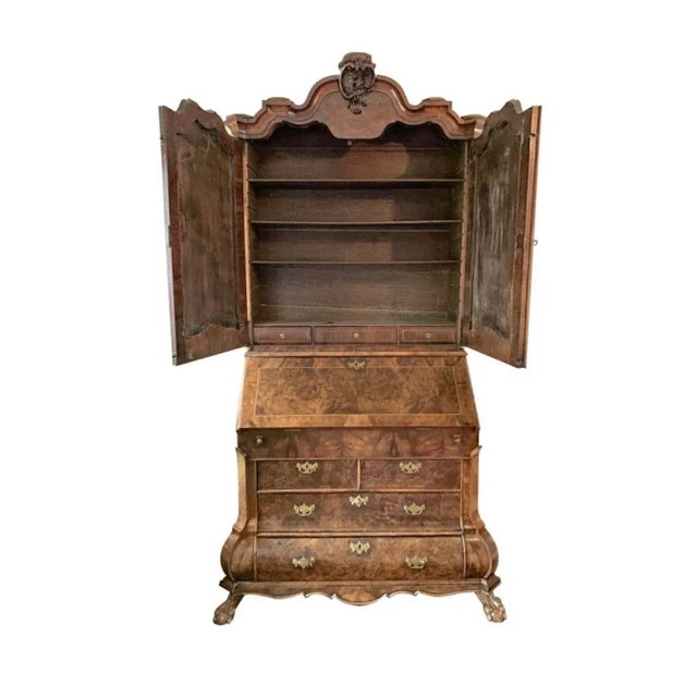 Richly carved drop-front secretary desk with interior storage Book matched wood doors Inlaid detailing Four lower draws...