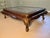 A large vintage rectangular coffee table with a rich mahogany-toned wooden frame, inset beveled glass top, scalloped...