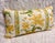 A beautifully custom-made lumbar pillow featuring a striking botanical floral stripe in warm golden yellow, fresh leafy...