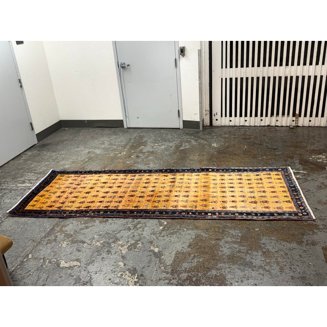 Design Plus Gallery presents a Vintage 3ft 5in × 9ft 5in Hand-Knotted Wool Tribal Runner Rug. A gold-tone field displays...