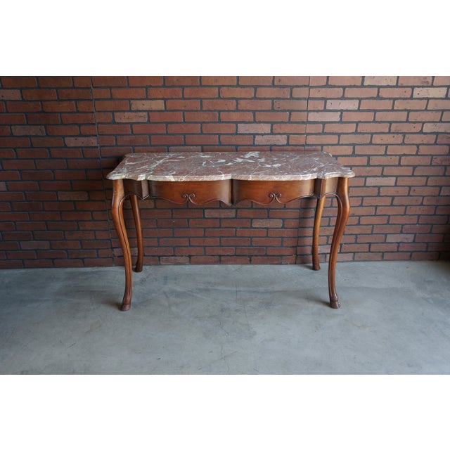 Charming Country French marble top console table. Crafted of walnut featuring cabriole legs grounded with pied de biche...