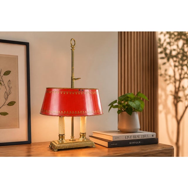 French-style bouillotte table lamp dating to the 1950s, with two candle-style fittings above a rectangular brass base. A...