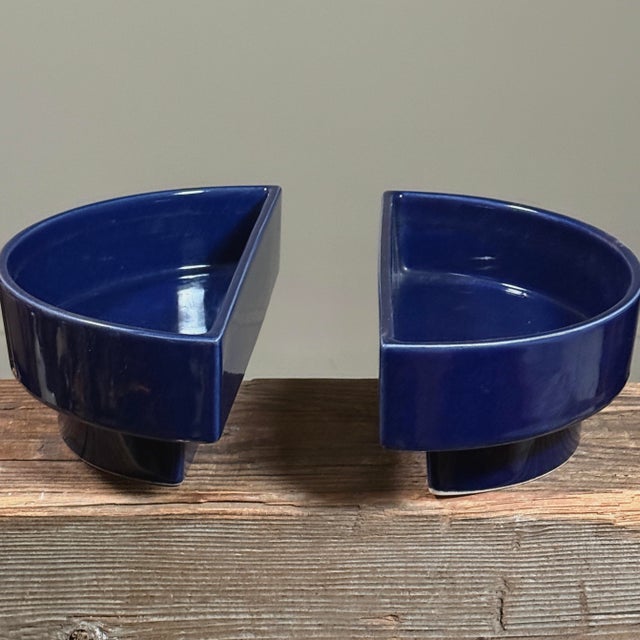 Each vessel is shaped as a half moon with a raised foot and finished in a dark blue glossy glaze. The inscription...