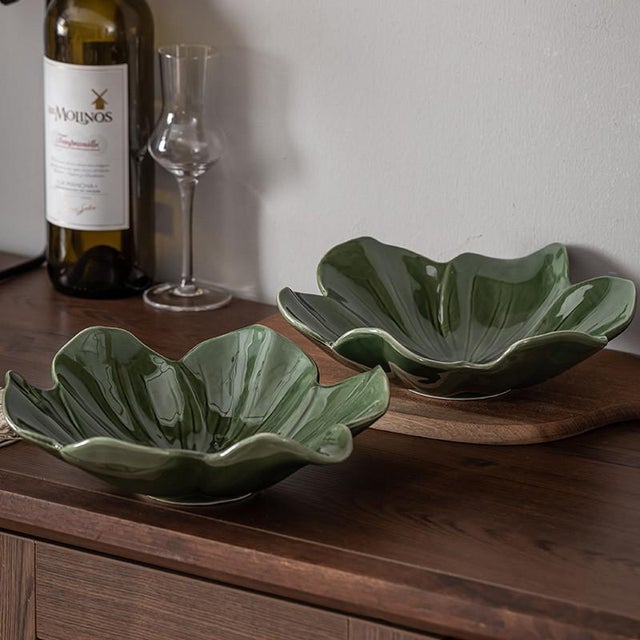 A pair of green, petal-shaped fruit dishes. Featuring a petal design with delicate veining, these pieces offer a fresh...
