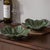 A pair of green, petal-shaped fruit dishes. Featuring a petal design with delicate veining, these pieces offer a fresh...