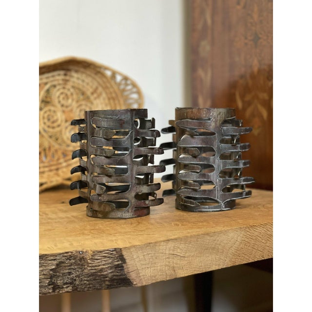 This pair of sculptural candle holders showcases a striking Brutalist design, crafted from hand-cut and welded metal with...