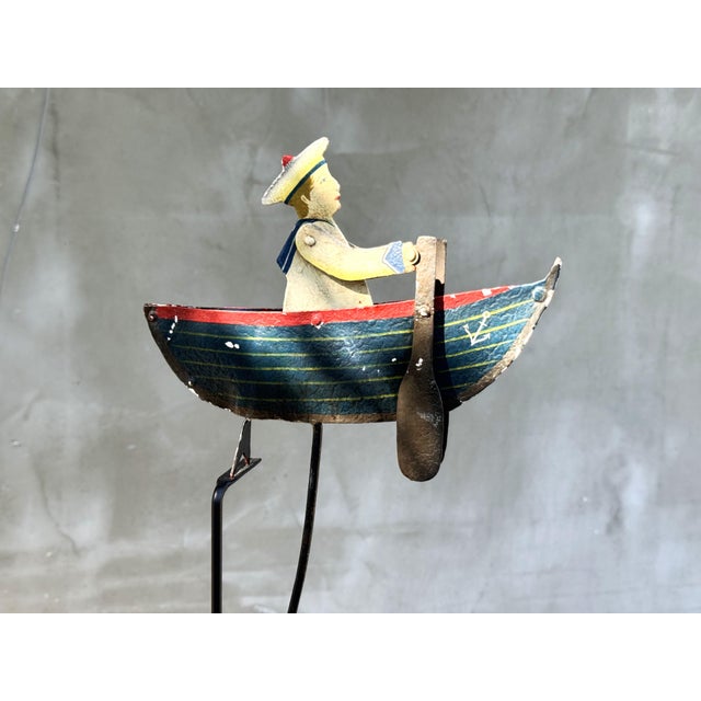 Whimsical vintage balancing sailor toy with hand-painted metal boat, articulated rowing mechanism, and poetic nautical...