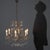 Burnished metal chandelier with scrolls and curls, embellished with glass beading. Six lights supported by curved arms,...