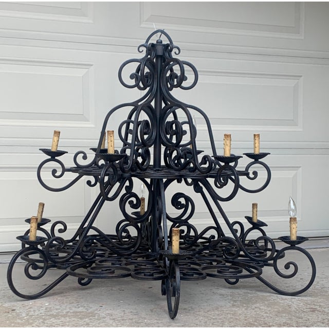 Enormous black, wrought iron chandelier fit for the entryway or kitchen of a queen. The chandelier has two tiers that are...
