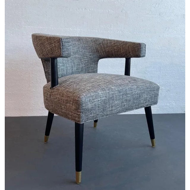 This mid-century modern accent chair features a sculptural, cut-out profile with an upholstered barrel back that connects...