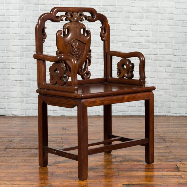 A Chinese Qing Dynasty period rosewood armchair from the 19th century, with hand carved splat and arm supports. Created in...