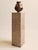 This tall pedestal features a rectangular column form with a richly textured surface, showcasing organic movement and...