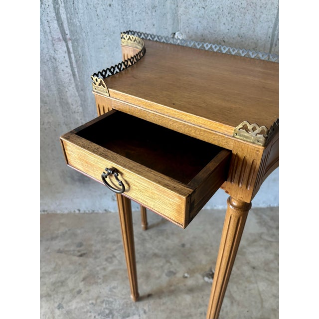 A French Louis XVI style console table featuring a serpentine front with curved sides, pierced bronze gallery, and a...