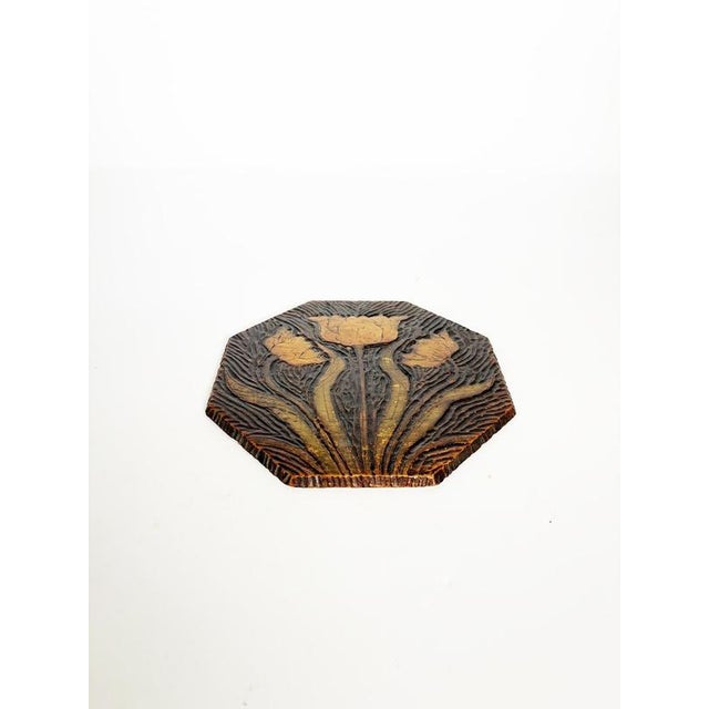 An elegant hexagonal carved wooden trivet, featuring a stylized floral design of three blooming tulips. Its flowing lines...