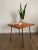 A vintage mid-century California modern style side table featuring heavy iron legs with ball feet and a red-toned plywood...