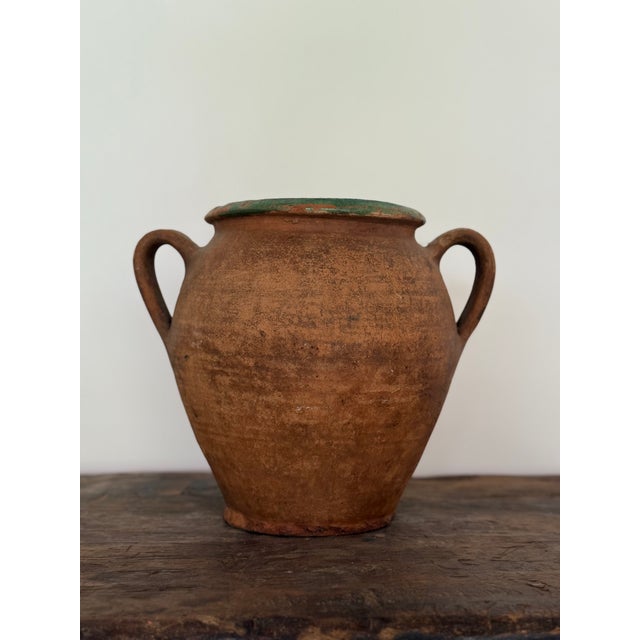 A traditional 19th-century French terracotta pot, once used for storing olives. Features a wide mouth, twin handles, and...