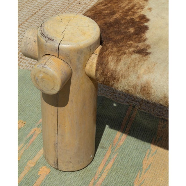 A sculptural vintage rustic bench featuring a hand-built solid log frame and an authentic cowhide sling seat. The...