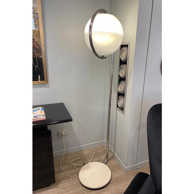 A 1970s floor lamp made of iron and glass, featuring a sleek iron stem and a glass globe. The lamp showcases a double-...