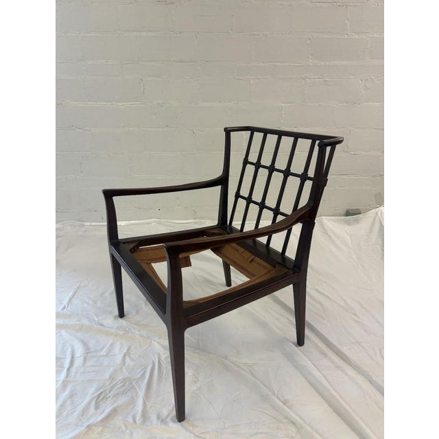 A handsome vintage Chippendale-style lounge chair featuring a pierced lattice back, sculptural open arms, and a richly...
