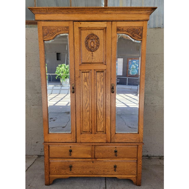 1920's English golden oak armoire with 2 beveled glass mirrored doors. Very nice condition with a glowing mahogany...