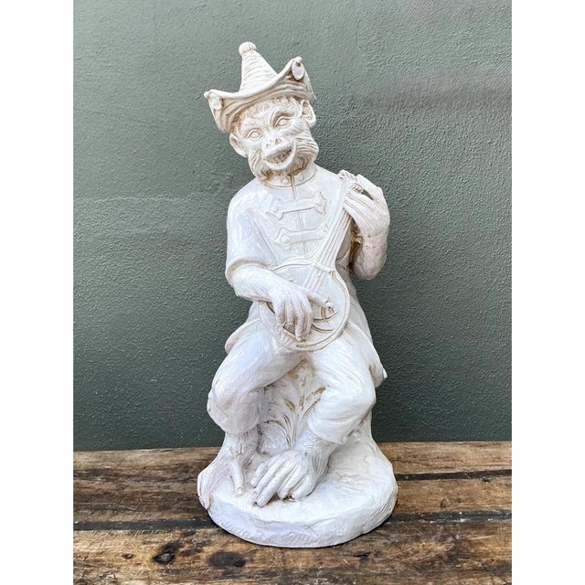 This vintage whimsical ceramic figure depicts an anthropomorphic monkey musician, seated with one leg crossed casually...