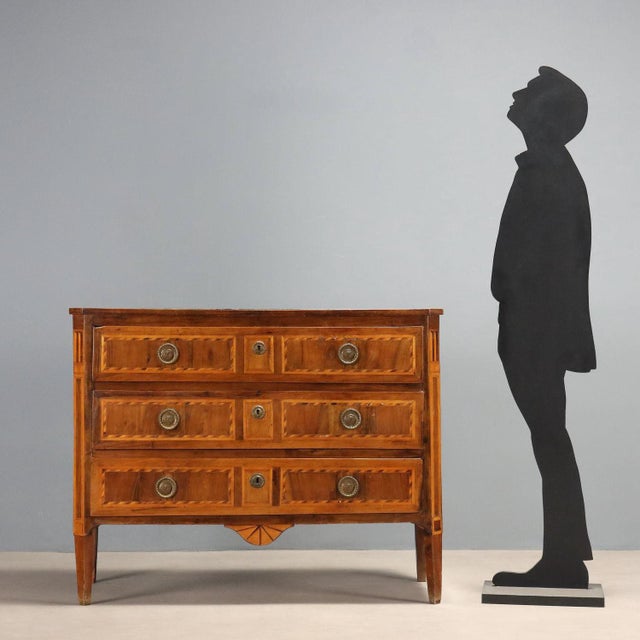 Neoclassical walnut chest of drawers with mahogany, maple, and walnut trim. The front features three tripartite drawers,...