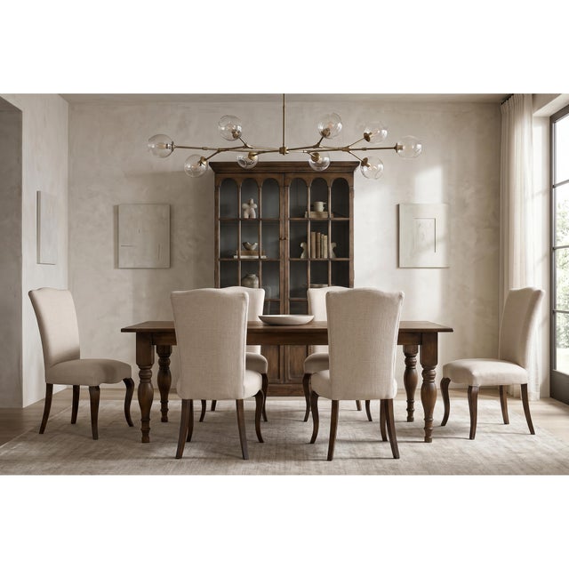 Dark brown cabriole legs curve outward beneath cream upholstery, drawing a French outline around the seat and back. The...