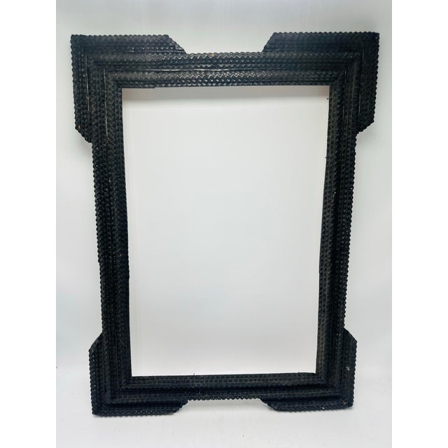A vintage tramp art wooden picture frame handcrafted from layered, chip-carved wood. The frame features the classic...