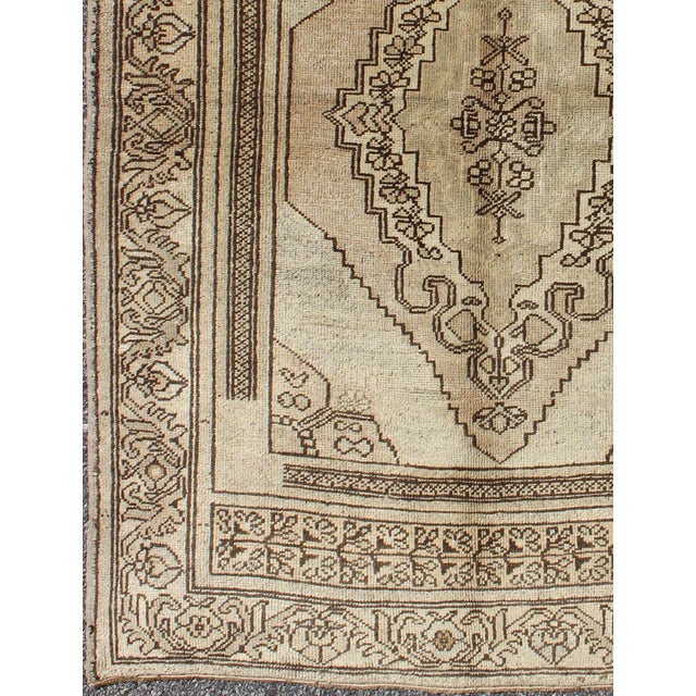 This Oushak rug features an intricately beautiful design. The central medallion is complemented by a defining border...