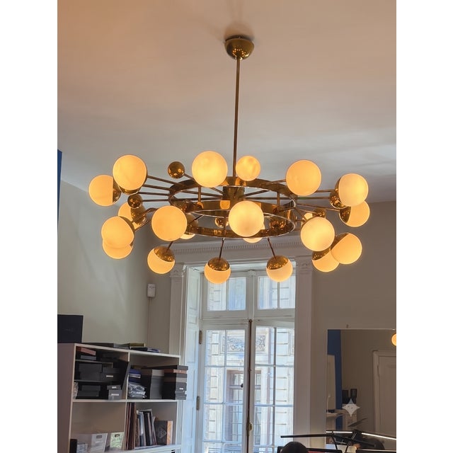 Playful and elegant brass mid-century modern chandelier illuminated by opaque glass bubbles. An object of atomic fascination.