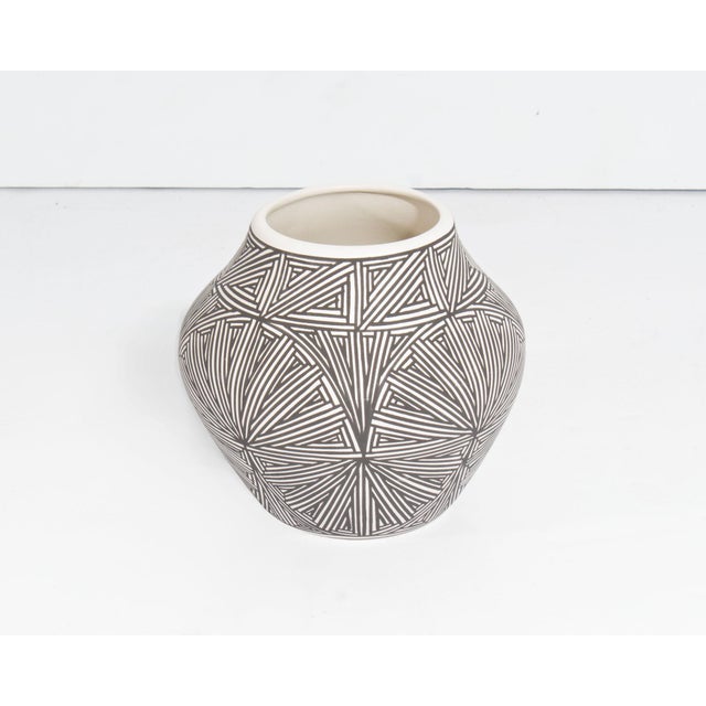 An Acoma Pueblo pottery vase by the ceramicst Debra Waconda. This vase features a rounded middle and a narrow base and...