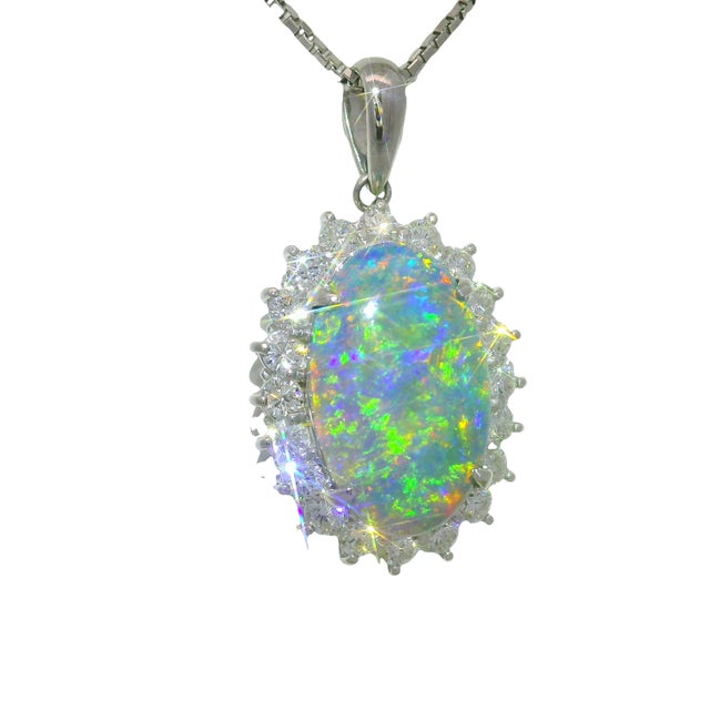 A captivating pendant showcasing a vibrant black opal, weighing 3.51 carats, surrounded by 1.01 carats of round-cut white...