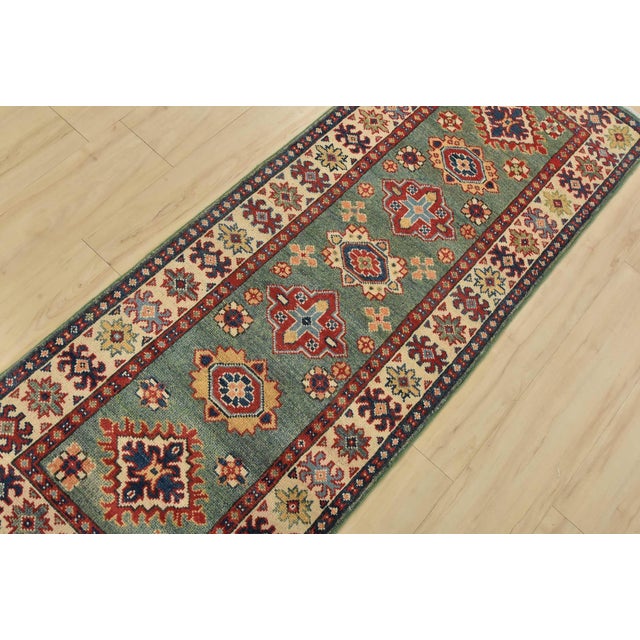 A tribal Caucasian Kazak runner hand-knotted with fine wool on a cotton foundation. This rug features a row of medallions...