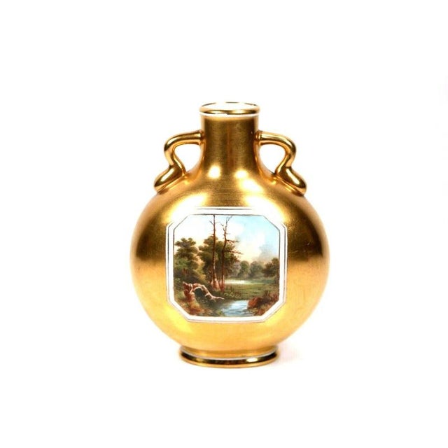 Lustrous burnished gilding completely encloses the exterior of this porcelain moon flask, extending seamlessly across the...