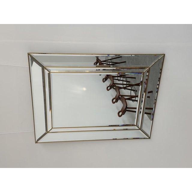 An elegant vintage wall mirror dating from the 1980s, featuring a beautifully architectural frame composed of wide beveled...
