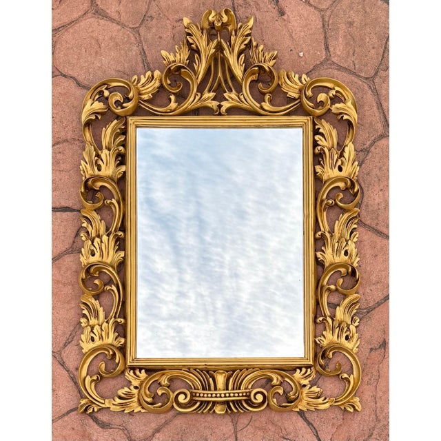 This ornate mirror reflects the Rococo style popularized in Europe during the 18th century, characterized by its curved...