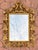 This ornate mirror reflects the Rococo style popularized in Europe during the 18th century, characterized by its curved...