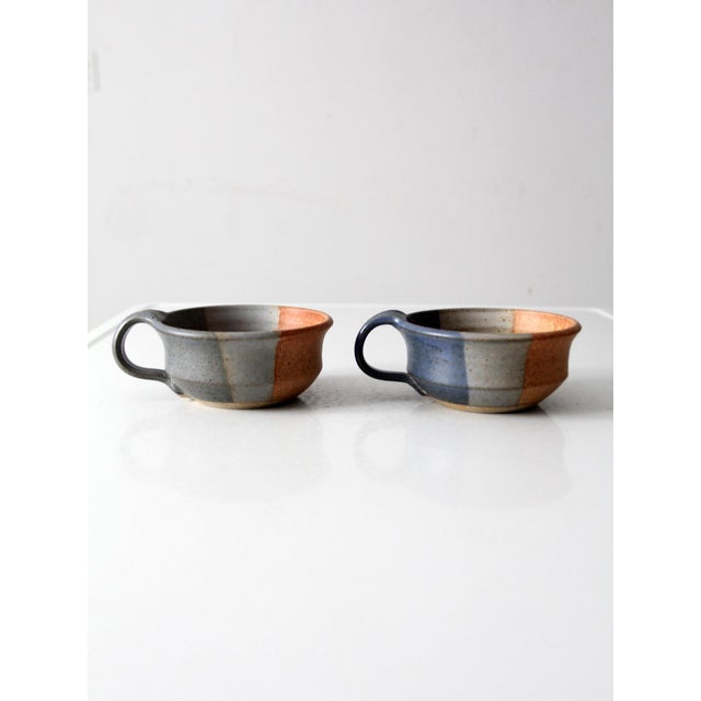 This beautifully balanced pair of vintage studio pottery soup cups is defined by gently rounded forms, sculptural handles,...
