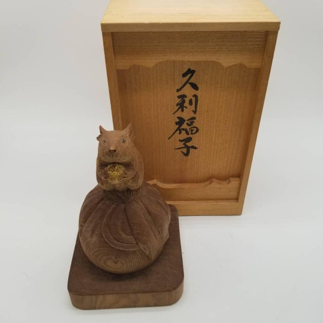 This is a vintage Japanese wooden figurine depicting a mouse standing atop a rounded base while holding a chestnut in its...